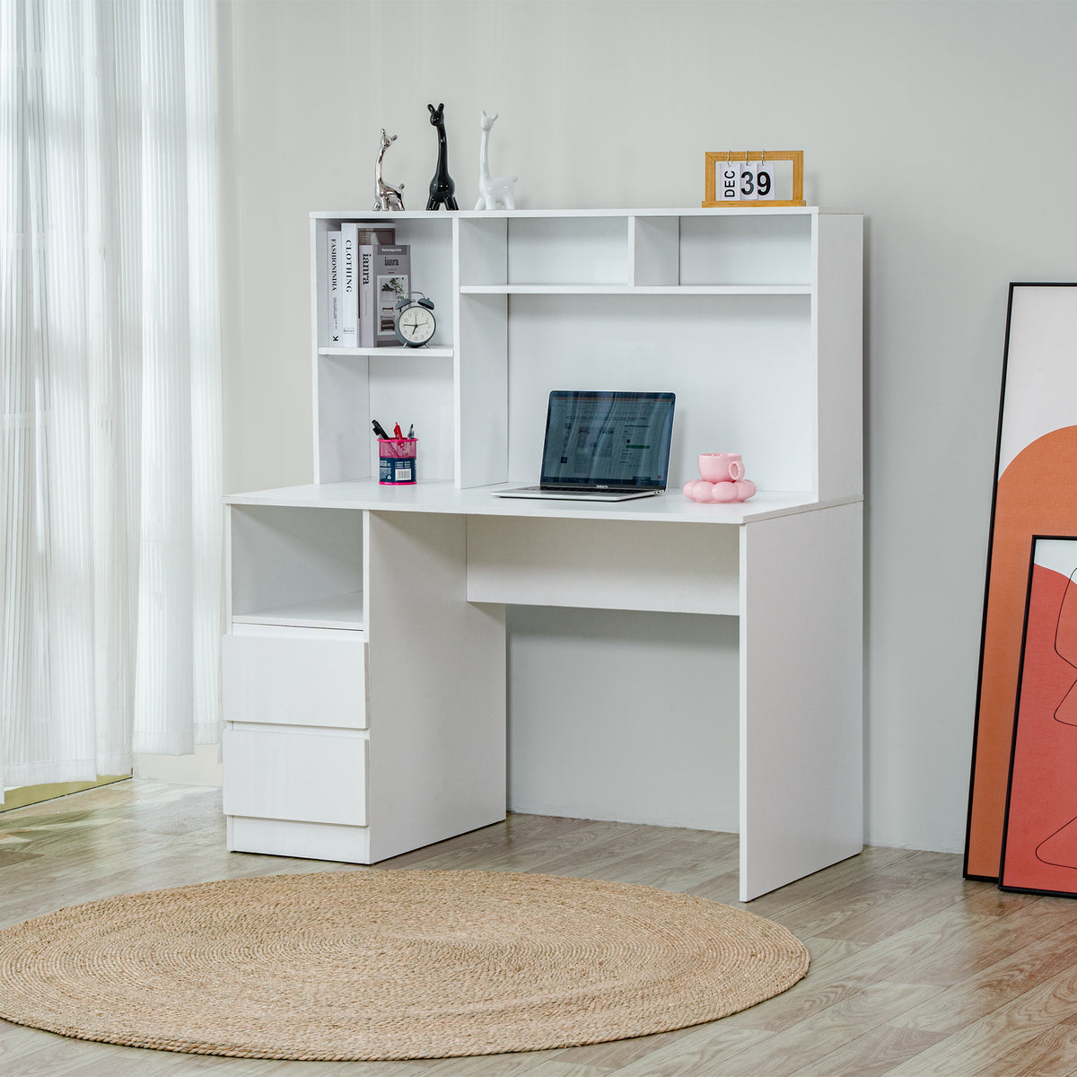 A white corner computer desk with an attached hutch, styled in a bright room with a woven round rug, curtains, and framed art.