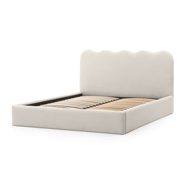 An upholstered bed frame with a tall, scalloped headboard in a light beige fabric, shown with wooden slats on a clean white background.