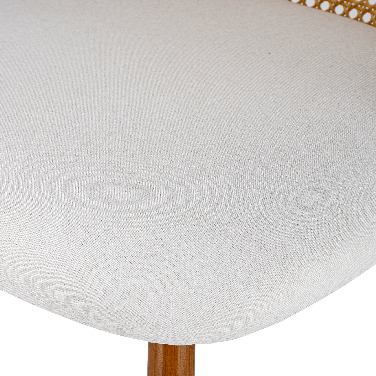 Close-up of a light beige textured fabric upholstered chair seat with a wooden leg visible at the bottom and part of a gold metal frame at the top edge.