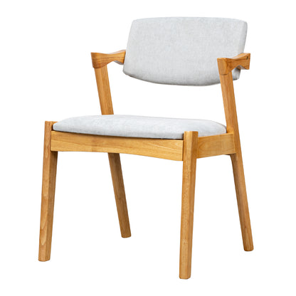 A modern wooden dining chair with a light oak frame and light gray upholstered seat and back cushion, shown on a plain white background.