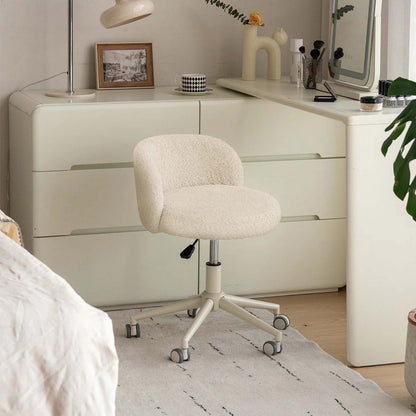 A cream-colored bouclé office chair with a five-star wheeled base, positioned in front of a matching cream-colored dresser in a styled bedroom or home office setting.