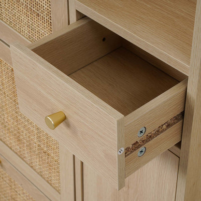 Close-up of a light oak wood cabinet with a drawer pulled open, featuring a round brass pull handle and a woven cane panel on the adjacent door.