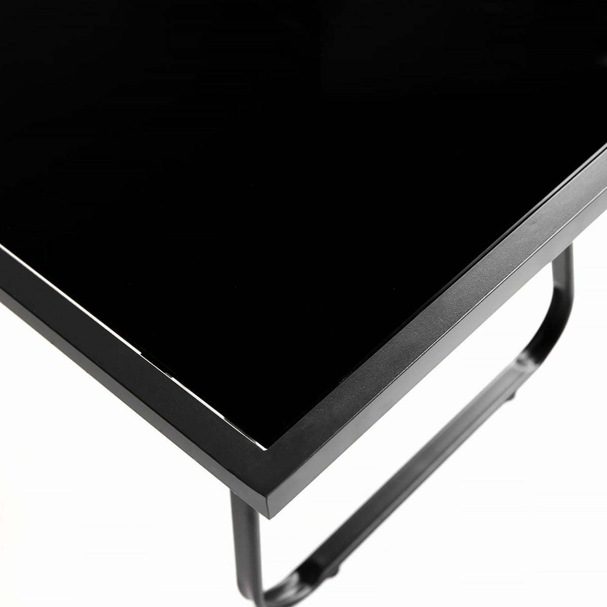 Close-up of a black glossy rectangular tabletop corner with a black metal frame and leg on a white background.
