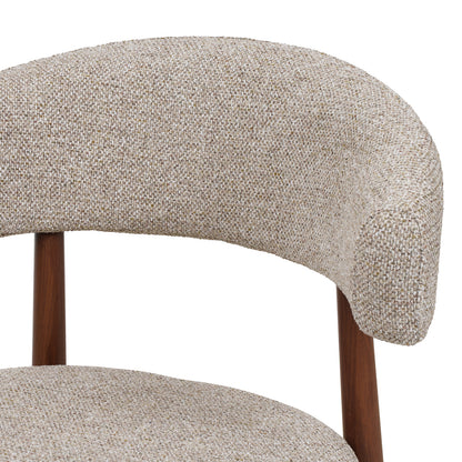 Close-up of a modern upholstered chair showing a curved backrest and seat in a textured beige tweed fabric, with dark brown wooden legs against a white background.